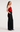 Side view of the Anisa red ruffle top styled with black wide-leg trousers.