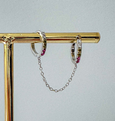 Annelis Huggie Chain Earrings in silver displayed on a gold stand against neutral background.