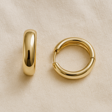 Gold elongated polished huggie earrings on white linen backdrop, Apress Huggie Earrings.