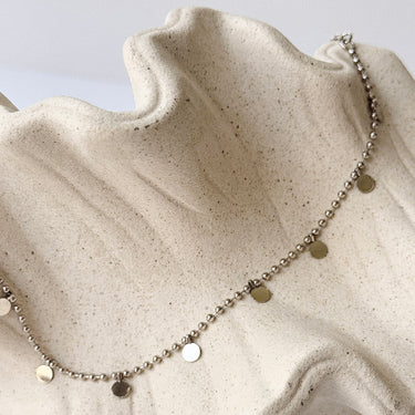 Aria Necklace by Matte, silver plated beaded necklace with disc charms on cream textured surface