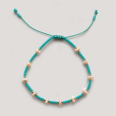 Arinet Bracelet in turquoise featuring vibrant turquoise beads, freshwater pearls, polished gold accents, and an adjustable turquoise cord.