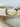 A gold-colored bracelet with a mix of solid and patterned beads displayed on a wooden surface by Matte