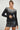 Woman wearing a black ribbed knit sweater with white contrast neckline, long sleeves, and slim fit — Aurora Sweater by Matte.