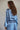 Model wearing the Misha Top in blue — satin long-sleeve crop top, relaxed fit, paired with matching skirt, elegant evening look.