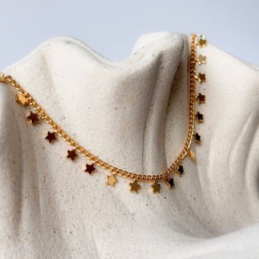 Belen necklace gold filled star charm chain on textured beige fabric background