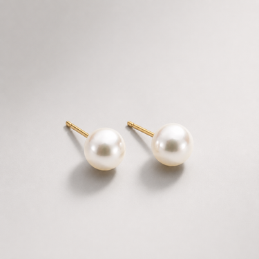 Bellota Stud Earrings pearl studs on neutral background, showing round pearl design and gold post detail.