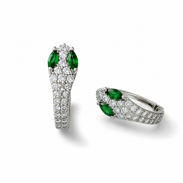 Silver pavé snake hoop earrings with emerald green marquise stones on white marble surface
