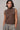 Woman wearing the Boon sleeveless mock-neck knit top in brown with crystal shoulder embellishments and a relaxed fit.