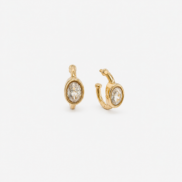 Braine Hoop Earrings featuring polished gold-plated hoop earrings with a bezel-set oval clear crystal charm, smooth rounded hoop silhouette, high-shine finish, secure hinged closure, lightweight design, and an elegant everyday style.