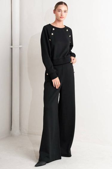 Woman wearing black pants with button details on a white background