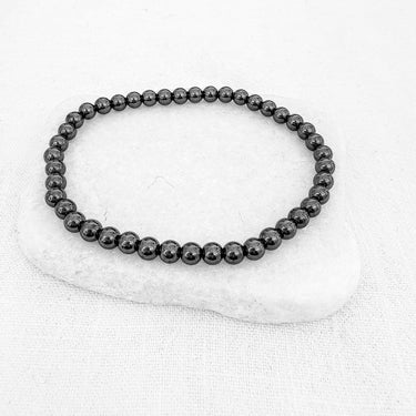 A black beaded ball stretch bracelet displayed on a white surface.