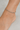 Silver beaded anklet on a person's ankle against a neutral background