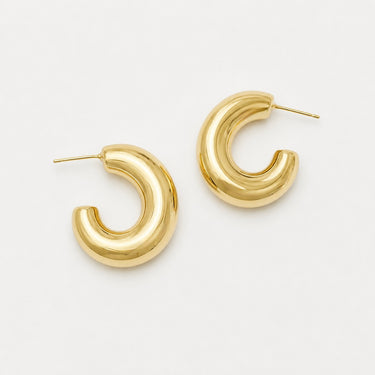 Clara Hoop Earrings featuring polished gold-plated open C-shaped hoop earrings with an elongated rounded silhouette, smooth high-shine finish, lightweight design, secure post-back closure, and a modern sculptural look.