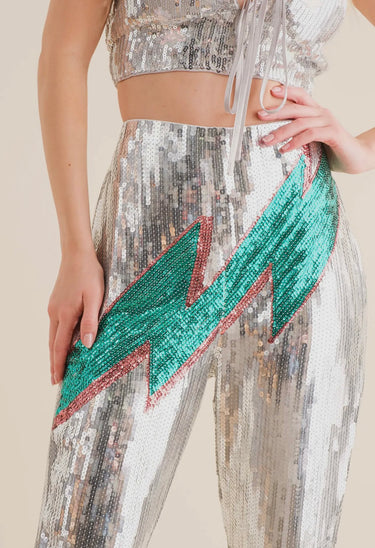 Silver sequin pants with bold green and red lightning bolt detail, high-waisted flared fit, close up