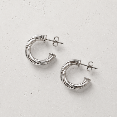 De Haan Hoop Earrings featuring polished silver-plated hoop earrings with a twisted rope-inspired texture, rounded hoop silhouette, mirror finish, secure hinged closure, lightweight design, and timeless everyday style.