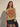 Model wearing the Drumar Graphic Tee in olive green featuring a bold vintage-inspired red snake graphic, structured cap sleeves, relaxed cropped silhouette, and crew neckline paired with a black mini skirt.