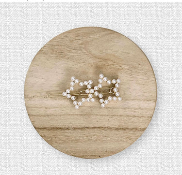 Duke Hair Clip with two silver star shapes adorned with pearls on light wood background, elegant accessory photo for Matte.