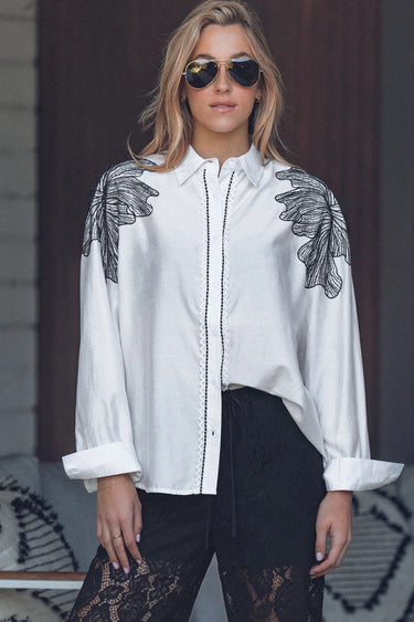 Elaine Shirt front view featuring crisp white fabric, collar neckline, and black embroidery.