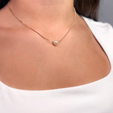 Woman wearing the Elara Necklace gold version with pearl pendant