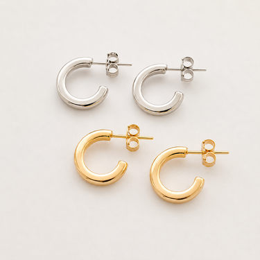 Emilia Hoop Earrings featuring polished gold-plated and silver-plated chunky mini hoop earrings with a smooth rounded silhouette, lightweight design, secure hinged closure, mirror finish, and timeless everyday style, displayed on a soft white background.
