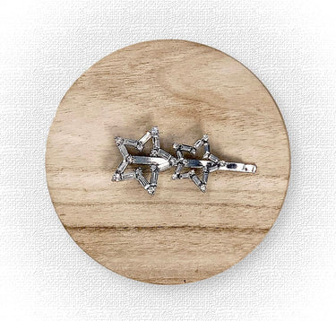 Silver star-shaped brooch on a wooden circular platform with a white background