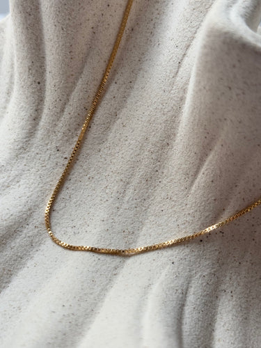 Encanto gold plated chain necklace by Matte, delicate flat chain on neutral fabric