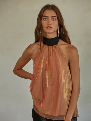 Woman wearing the Eos Halter Top in sheer golden-rose fabric with black ribbon halter tie, photographed against a neutral background.