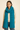 Woman wearing the Eto Pashmina in teal wool knit with airy texture, soft natural light, Matte.