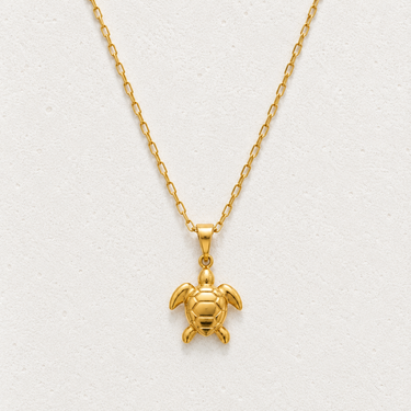 Exuma Necklace featuring a polished gold-filled sea turtle pendant suspended from a delicate chain, styled on a light neutral background showcasing its timeless coastal-inspired design.
