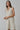 Model wearing natural linen Ezeiza Dress with fringed V-neckline.