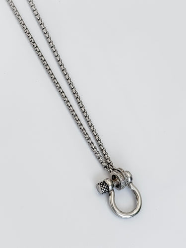 A gold-plated necklace with a small horse charm on a white background.