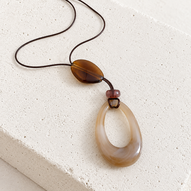 Fevi Necklace featuring a sculptural cream and brown teardrop resin pendant on a dark cord.