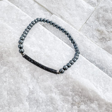 A stretch bracelet with black and white beads, displayed on a textured surface by Matte Jewelry