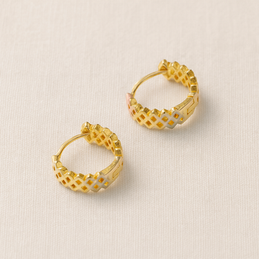 Flora Huggie Earrings, champagne gold huggie hoop earrings with open lattice cut-out design and polished mirror finish, photographed on white linen background with soft editorial lighting