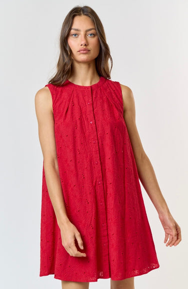 A woman wearing a vibrant red, sleeveless summer dress with a floral eyelet pattern, featuring a button-down front.