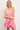 A woman wearing a pink eyelet summer dress with spaghetti straps and a v-neckline.