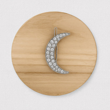 Hex Hair Clip shaped like a crescent moon with crystals on wood background, celestial accessory photo for Matte.