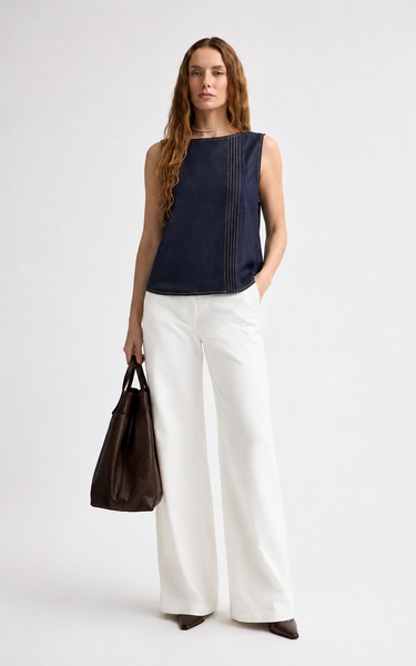 Woman wearing the Hotflix navy denim sleeveless top with white wide-leg pants and a brown handbag.