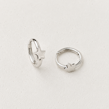 Idon Huggie Earrings featuring polished silver 12mm huggie hoops with delicate star accents and a secure hinged closure, styled on a white background showcasing their minimalist everyday design.