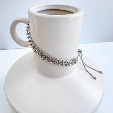 Three gold-plated chain bracelets displayed on a white cup and saucer, representing the product's adjustable and stylish nature by Matte Jewelry.