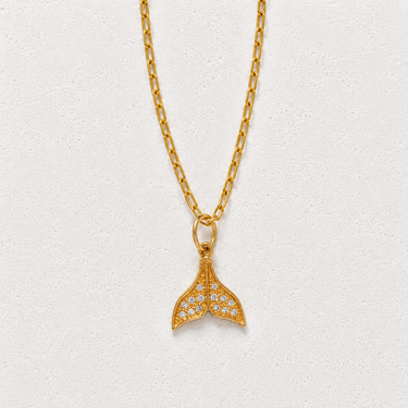Jared Necklace featuring a delicate gold-tone chain with a small mermaid tail pendant accented with sparkling clear stones on a soft white background.