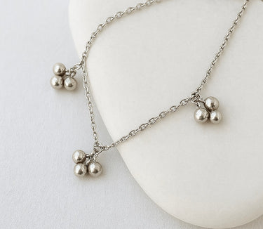 Silver anklet with three-ball pendants on a white background