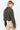 Olive green Kairo Blouse with structured pintucks and modern cropped fit, styled with beige tailored trousers on a bright white backdrop, back view.