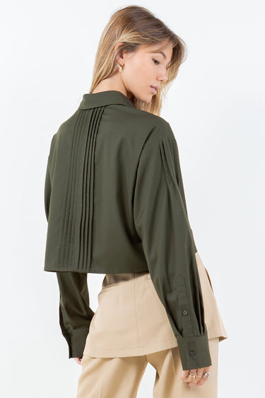 Olive green Kairo Blouse with structured pintucks and modern cropped fit, styled with beige tailored trousers on a bright white backdrop, back view.