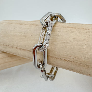 Bold silver chain bracelet with pavé crystal link detail displayed on wooden stand