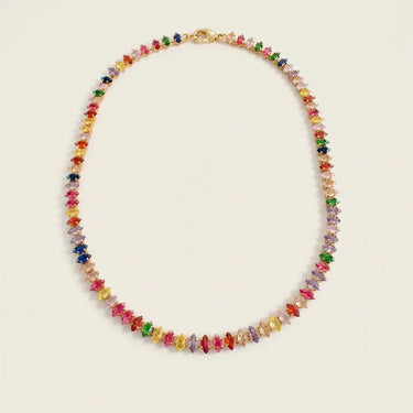 Kiron Necklace rainbow tennis necklace with multicolored cubic zirconia stones and gold-plated setting on neutral background.