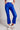 Model wearing cobalt blue slim pants with coated finish and white top — modern city look.