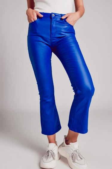 Model wearing cobalt blue slim pants with coated finish and white top — modern city look.