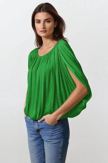 Woman wearing the Kyoto Blouse in green, lightweight draped top with soft pleats and relaxed fit, photographed on clean white background with natural light.