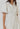 Model wearing white Lariatt Dress with puff sleeves, waist tie, and button-down front.